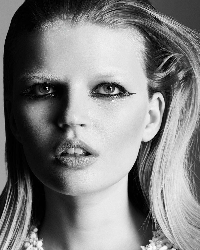 Black and white close-up beauty portrait of a woman with graphic winged eyeliner and slicked-back hair.