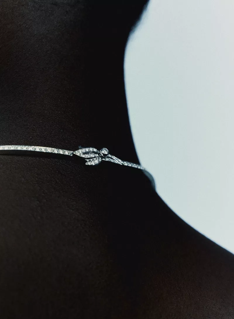 Close-up of a diamond pavé choker necklace worn around a model's neck in profile against a light studio background.