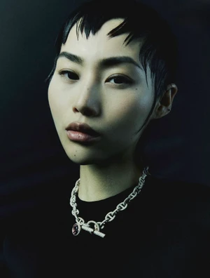 Close-up portrait of model Wawa Li wearing a silver link chain necklace against a dark background