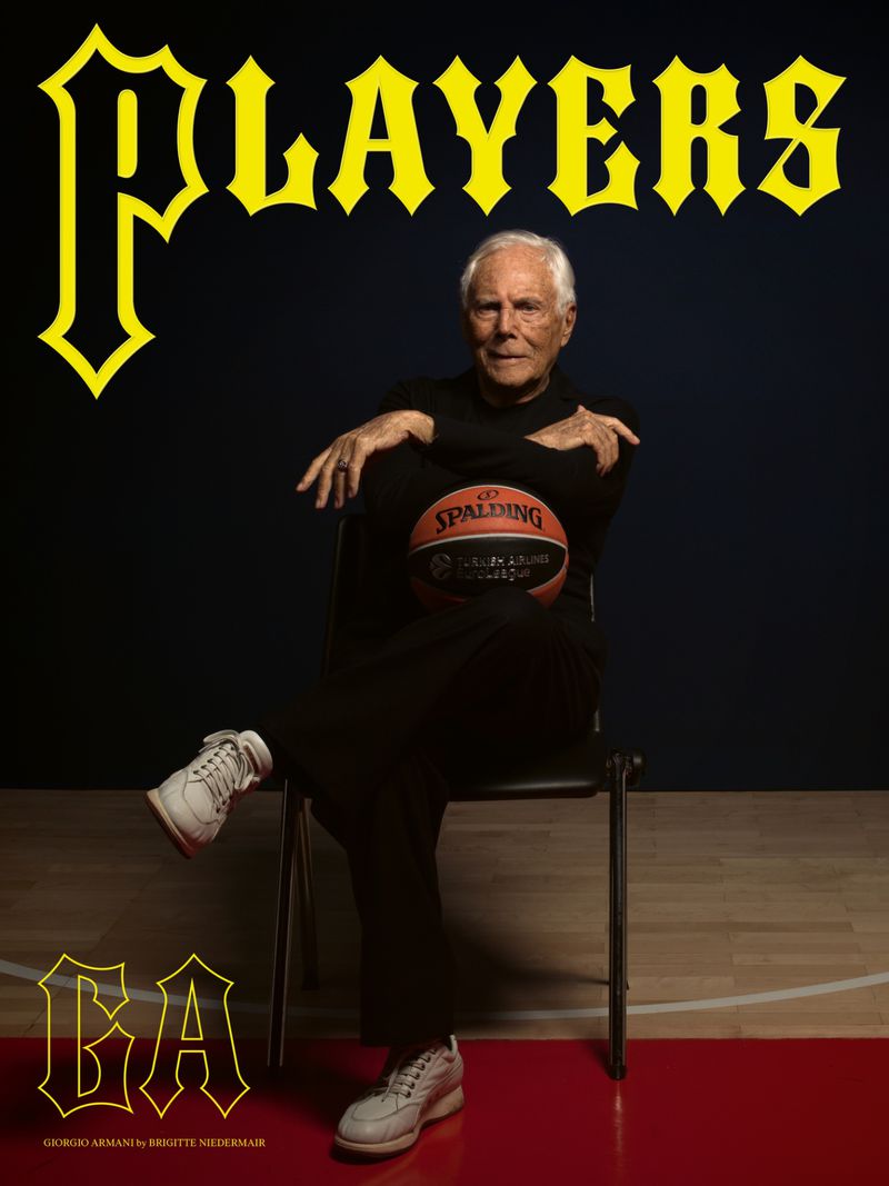 Giorgio Armani sitting in a chair, holding a basketball, wearing black clothing, and white sneakers, with the word 'Players' above him.