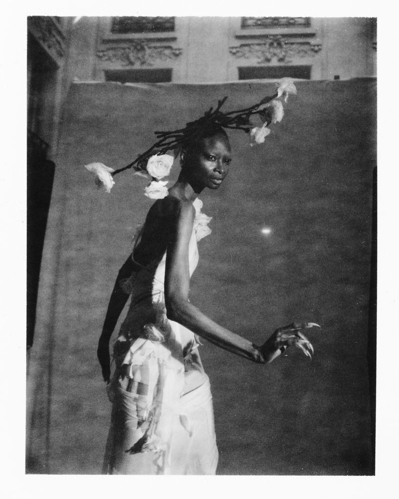 Black and white editorial portrait of model Debra Shaw wearing an avant-garde floral branch headdress and draped gown.