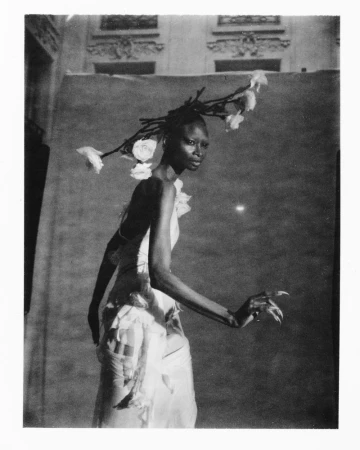 Black and white editorial portrait of model Debra Shaw wearing an avant-garde floral branch headdress and draped gown.