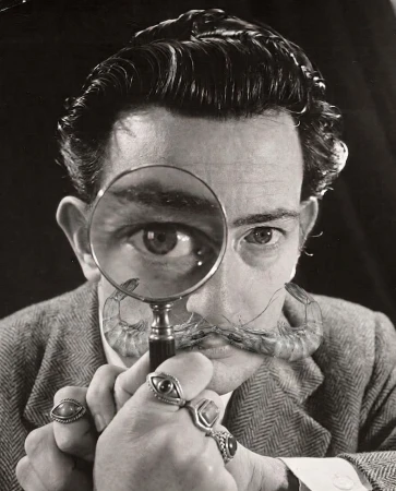 Surreal black and white portrait of Salvador Dalí looking through a magnifying glass with shrimp forming his mustache.