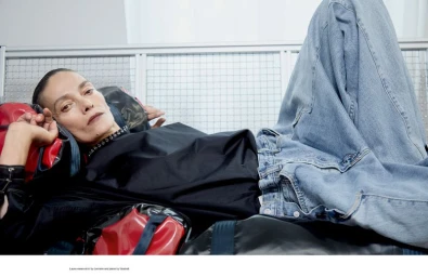 Model Laura Ponte reclining in blue jeans and a black shirt against a metallic grate backdrop for endless magazine