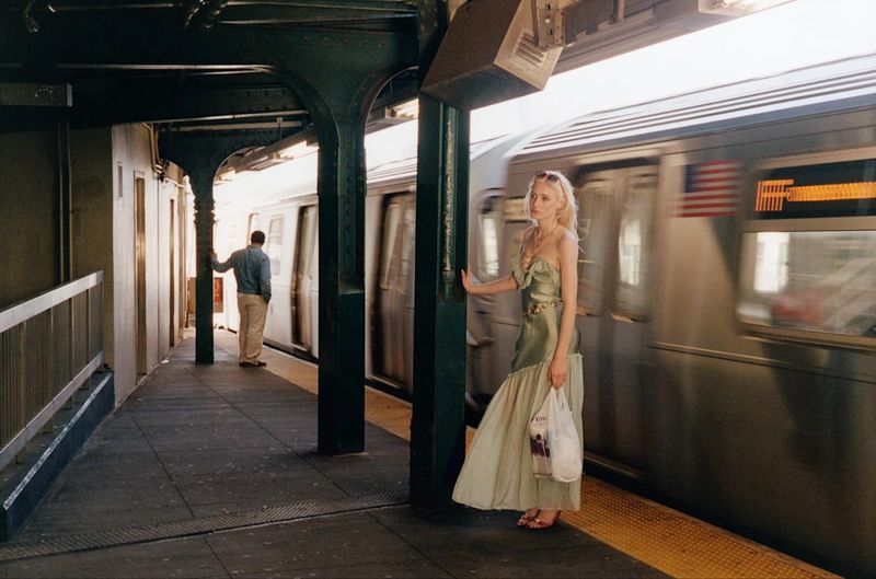 Model Summer Dirx standing on a subway platform in a light green gown next to a moving train for She'll Take Manhattan editorial.