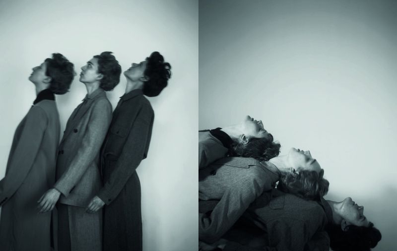 Three women in matching outfits lean their heads back in a modern black and white fashion editorial on a plain backdrop.