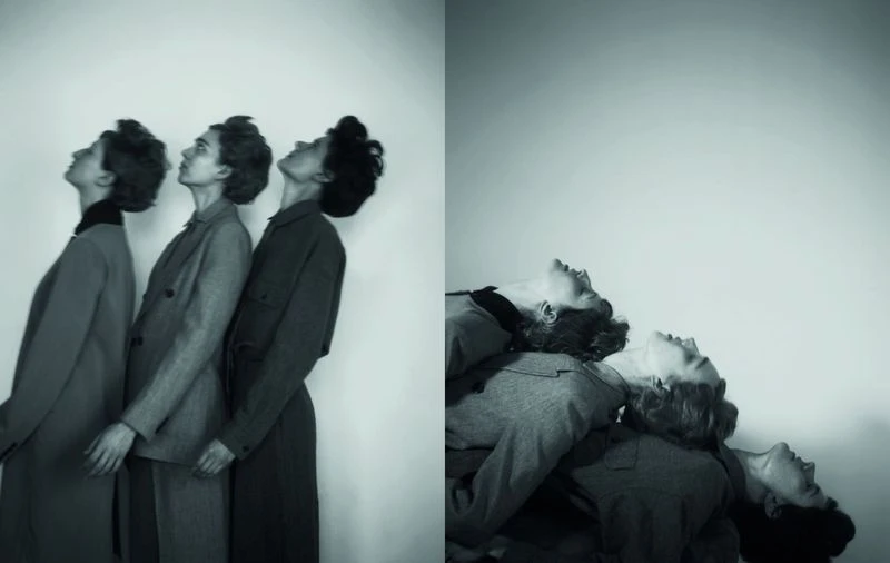 Three women in matching outfits lean their heads back in a modern black and white fashion editorial on a plain backdrop.
