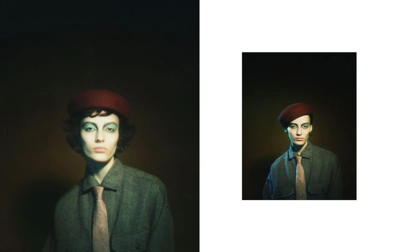Model wearing a grey shirt, tie, and red cap with dramatic eye makeup in an editorial image by Olivia Arthur for CAP 74024.