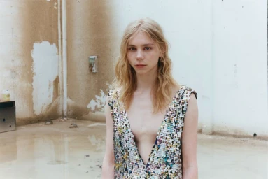 Model Rafe Crane-Robinson wearing an iridescent plunging sequin top against a distressed concrete wall with standing water.