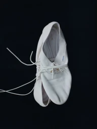 Pair of white soft leather lace-up flat shoes tied together by thin strings against a solid black background.