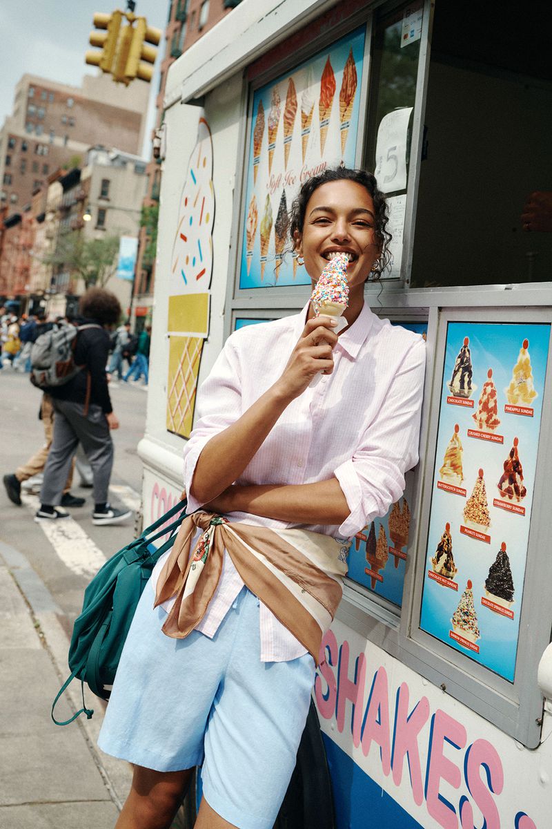 Nikita Wiorek smiling while eating an ice cream cone and leaning against an ice cream truck on a city street.
