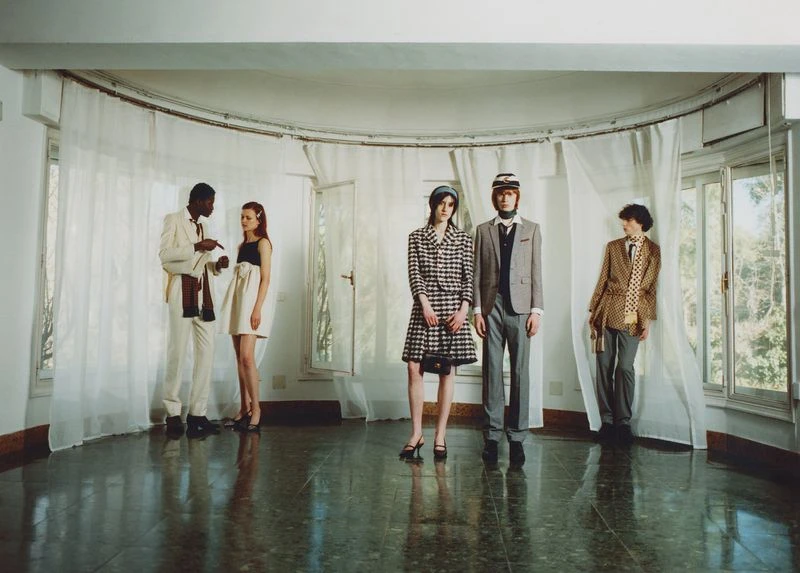 A group of fashion models in vintage clothing poses in an airy room with natural light, showcasing a retro aesthetic and classic style.