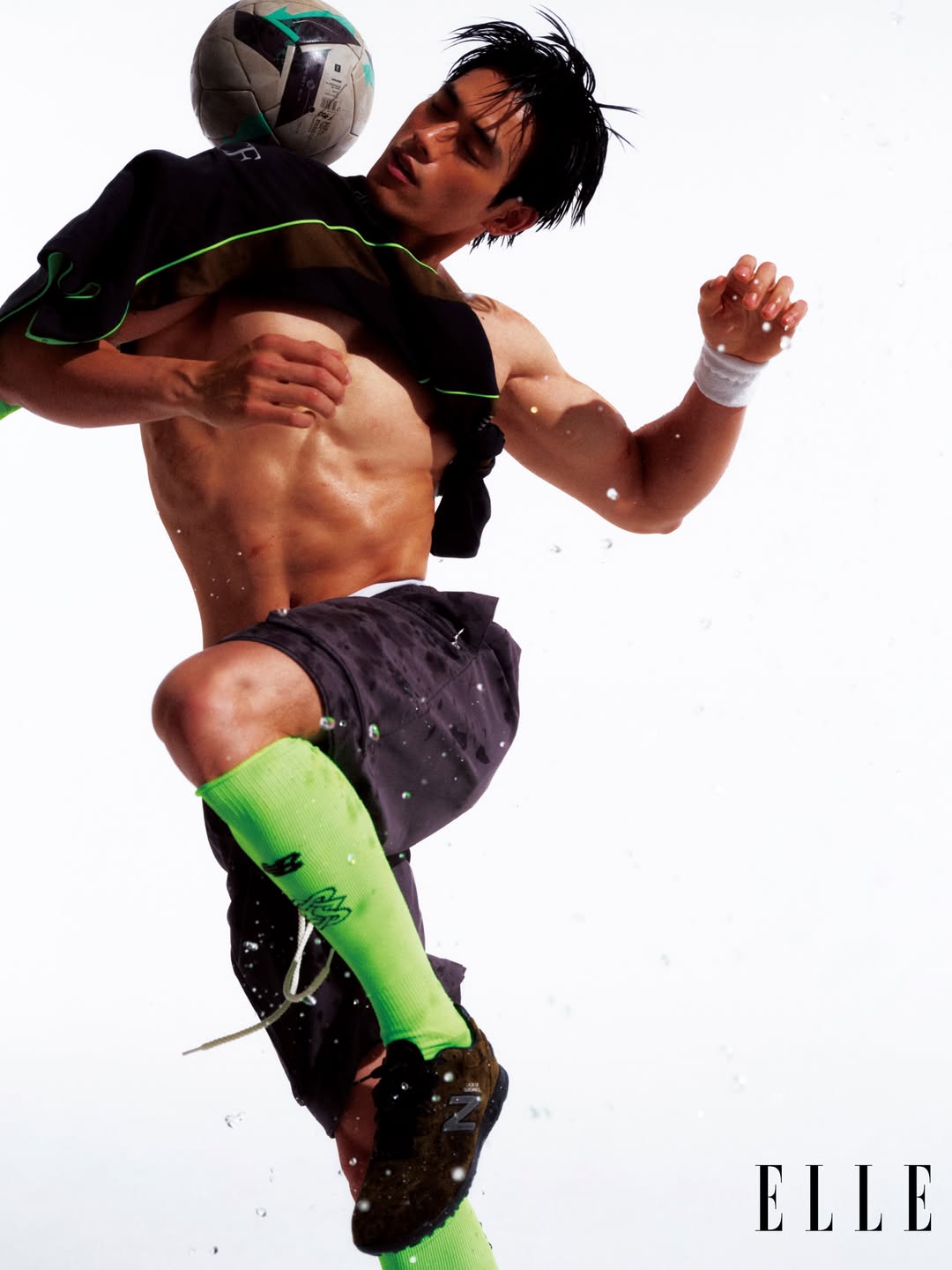 Shirtless male model balancing a soccer ball on his chest against a bright white studio background for Elle China World Cup project.