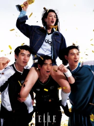 Woman held on shoulders holding a golden trophy surrounded by three men cheering under falling gold confetti on a white backdrop.