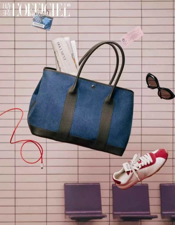 Fashion editorial shot of a denim tote bag with accessories, including a sneaker, sunglasses, a magazine, and a cable, floating mid-air.