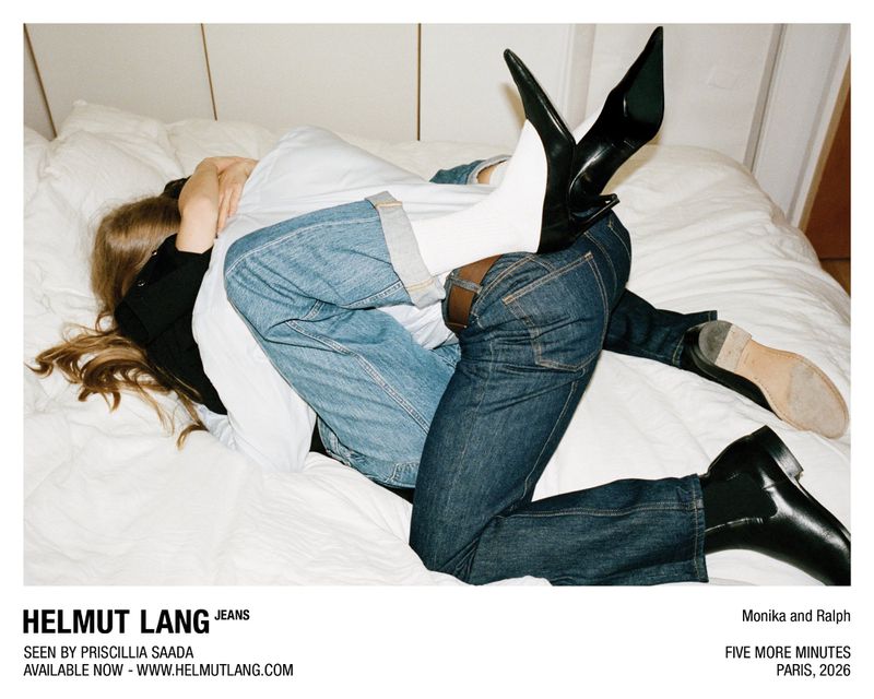 Two people intertwined on a white bed wearing Helmut Lang denim jeans, pointed black heels with white socks, and black leather boots.