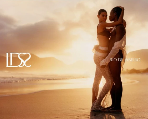 Two models embracing intimately on a sandy beach at sunset during the Ludovic de Saint Sernin swim 2026 campaign.