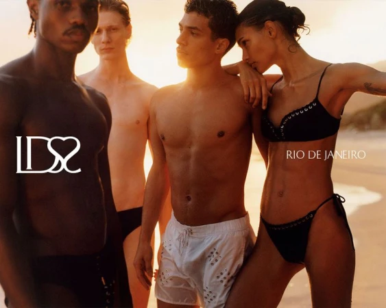 Group of four models posing on a sandy beach at sunset for Ludovic de Saint Sernin campaign