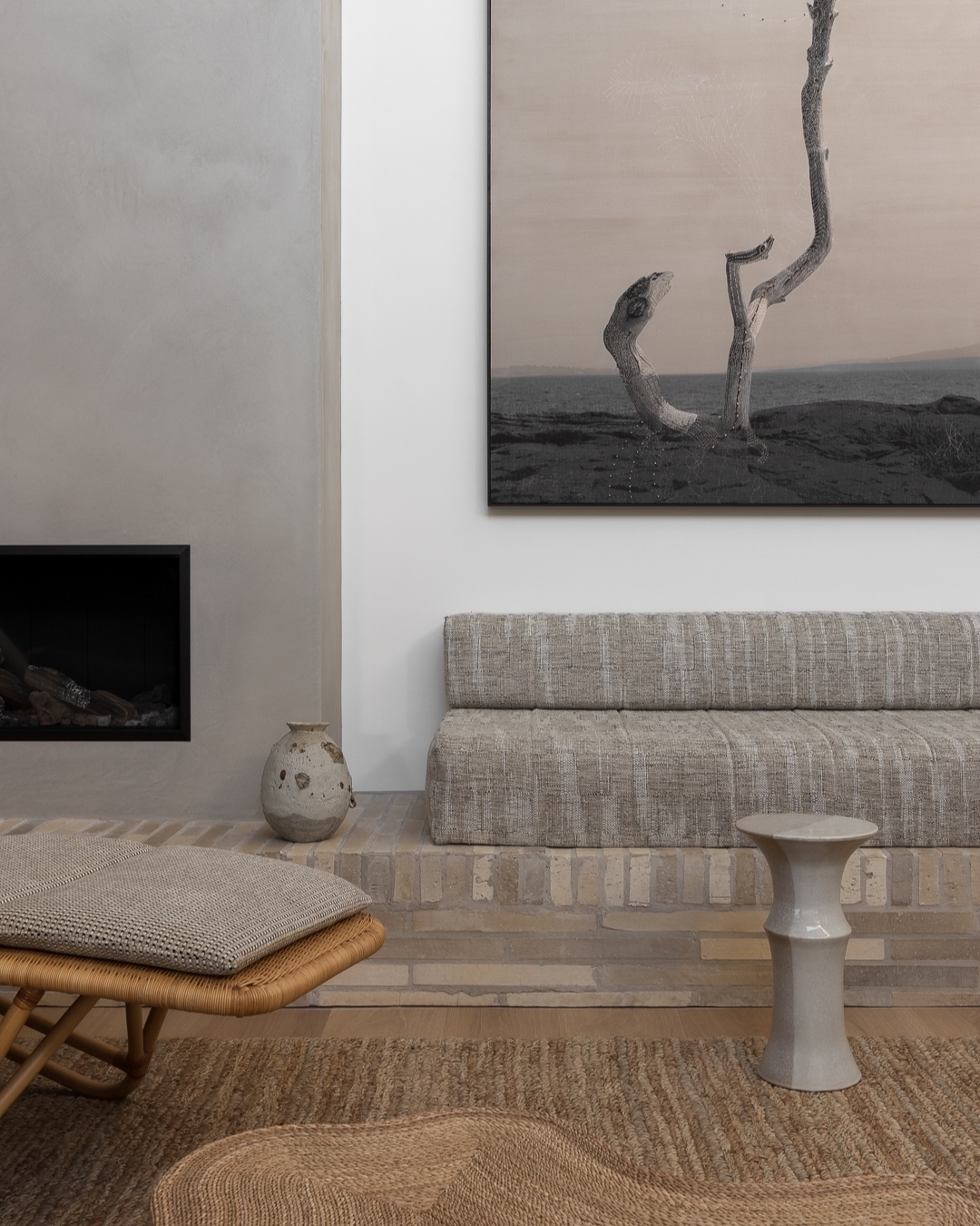 Interior shot features a neutral palette, textured furniture, a modern fireplace, and a serene abstract art piece above a light gray sofa.