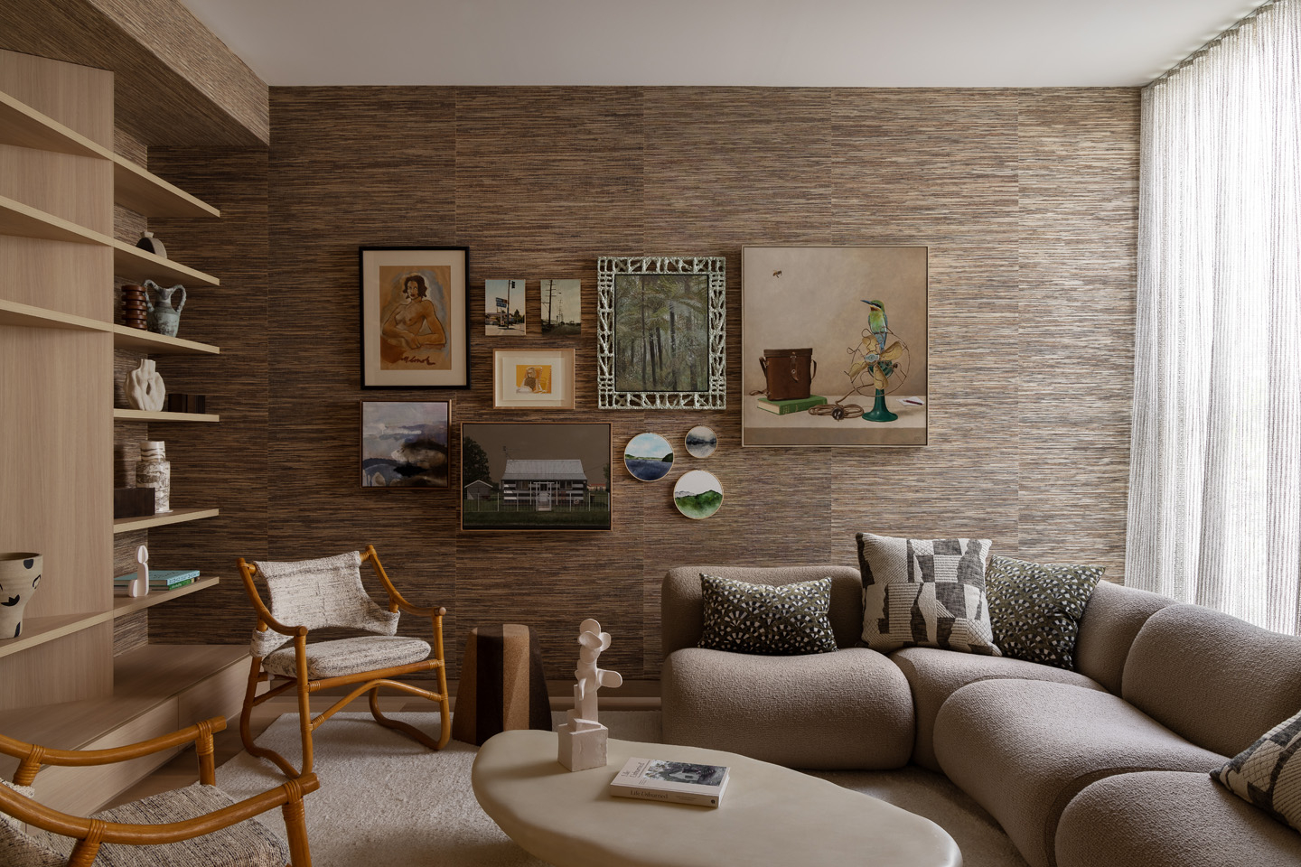 Cozy living room interior with a sectional sofa, woven chairs, wall art, neutral color palette, and soft natural lighting.