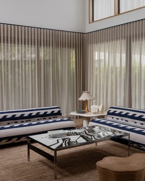 Modern living room featuring patterned blue and white sofas and sheer curtains under high ceilings
