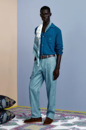 Model in a blue knit cardigan and light blue trousers wearing a patterned scarf for Etro spring summer 2026 men's lookbook