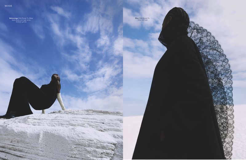 Fashion editorial spread featuring a model in black silhouette garments against a bright blue sky and white desert landscape.