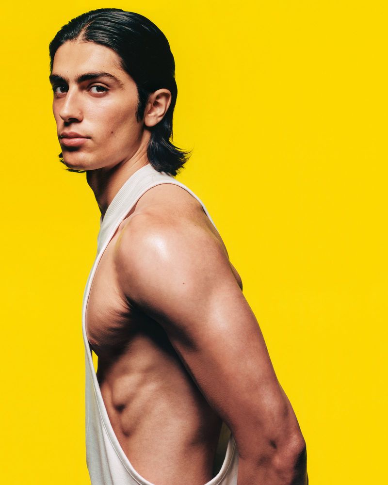 Profile portrait of a male model wearing a white tank top against a bright yellow background for Circle Zero Eight.