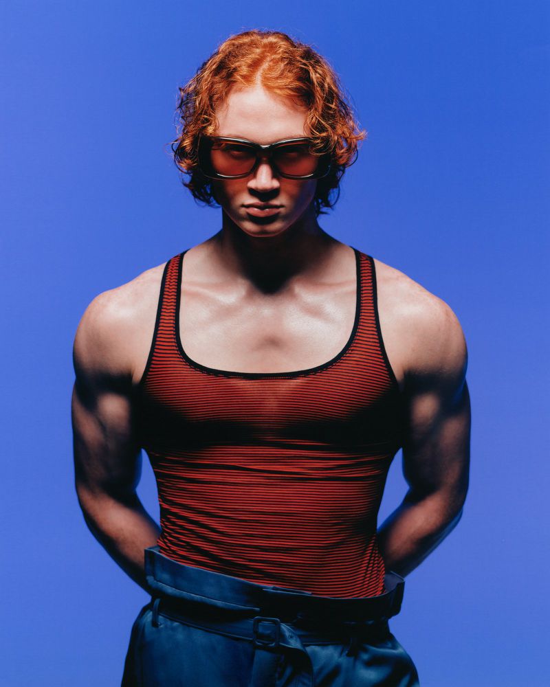 Model Taino Uppal wearing red tank top and sunglasses against blue backdrop for Circle Zero Eight Tifosi editorial