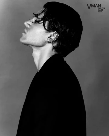 Antonio Medugno in profile looking upward wearing a spiked ear cuff and dark jacket in a black-and-white studio portrait.