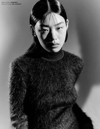 East Asian model Zimeng wearing a black mohair turtleneck sweater and hoop earrings in a monochrome studio portrait.