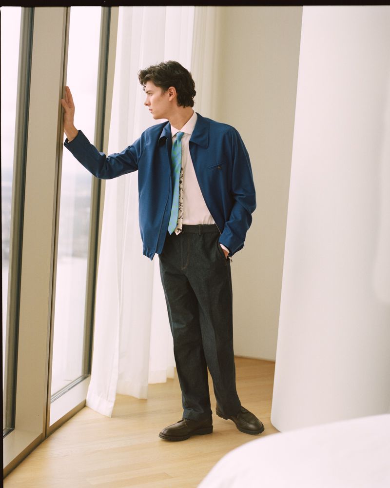Count Nikolai of Monpezat in a blue jacket and dark trousers standing by a floor-to-ceiling window looking outside.