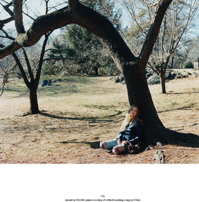 Model leaning against a large tree trunk in a park setting for Middle Plane Magazine editorial Secrets Out