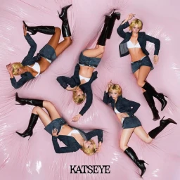 Members of Katseye in denim outfits and black knee-high boots reclining across an inflated pink vinyl surface.