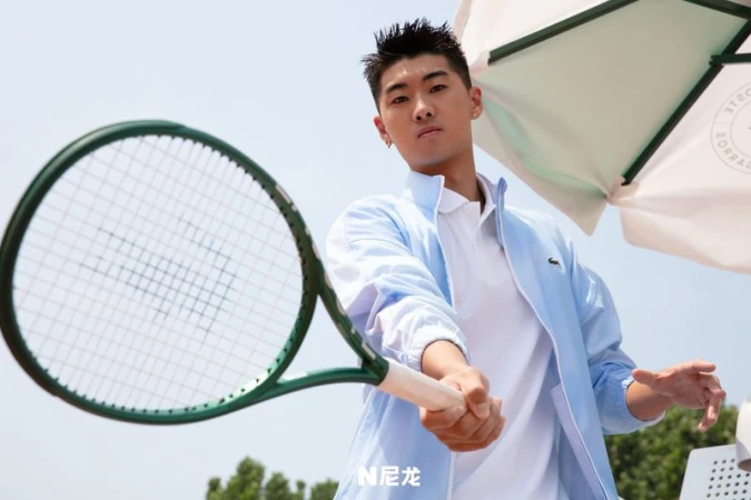 Man in sports attire poses with a tennis racket outdoors on a sunny day, capturing an athletic and dynamic moment with sports equipment.