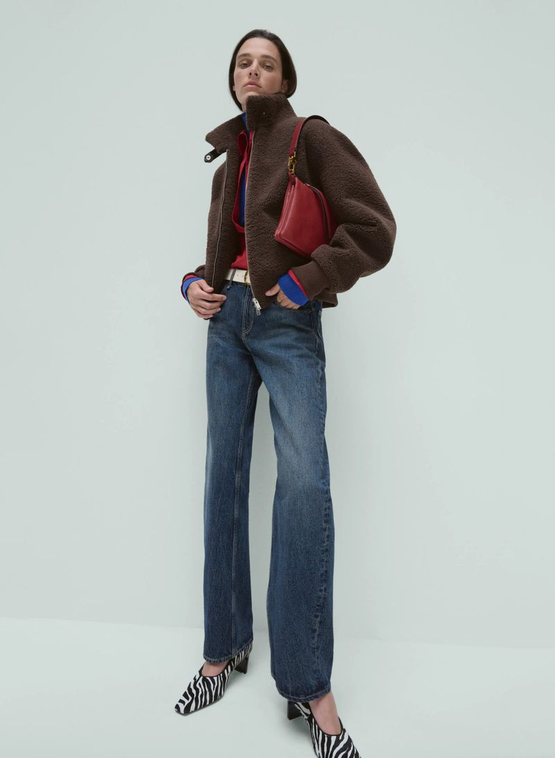 Model Leila Goldkuhl wearing a brown fleece jacket, wide-leg blue jeans, and zebra-print heels for Rag & Bone.