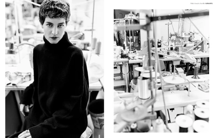 Black and white portrait of a short-haired woman wearing a black turtleneck sweater in an industrial garment workshop.