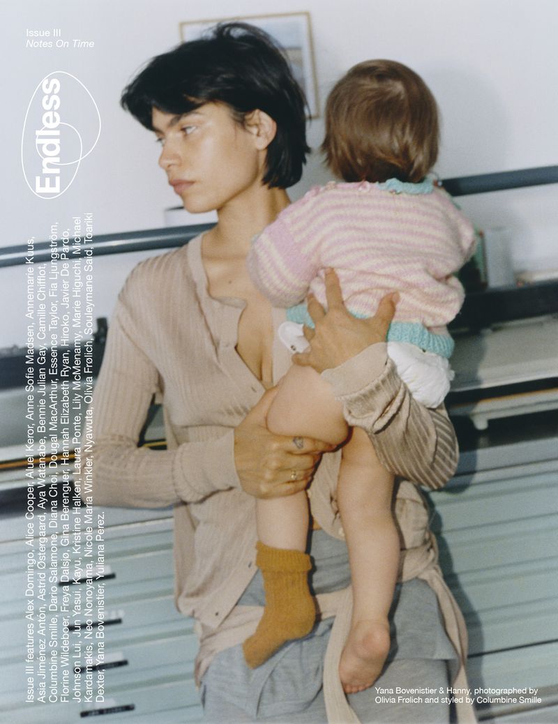 Magazine cover featuring a woman holding a baby. The woman has short dark hair and is wearing a light cardigan, while the baby is in a knit sweater.