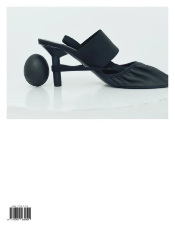 Black kitten heel shoe and black egg on a white reflective surface, showcasing footwear and minimalistic still life photography.