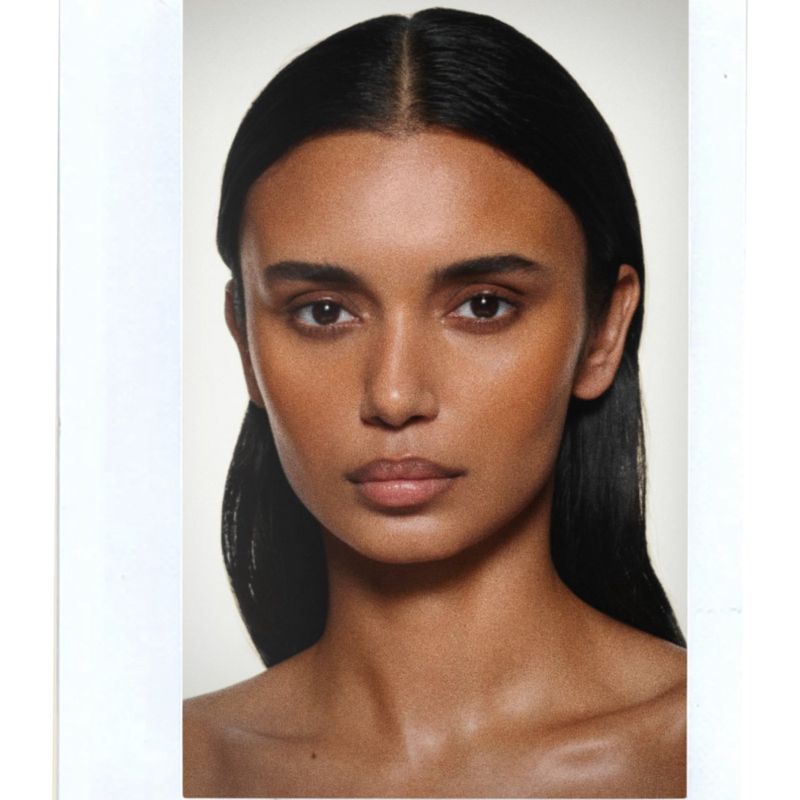 Beauty portrait of model Madhulika Sharma with center-parted dark hair against a white background for Victoria Beckham Beauty.