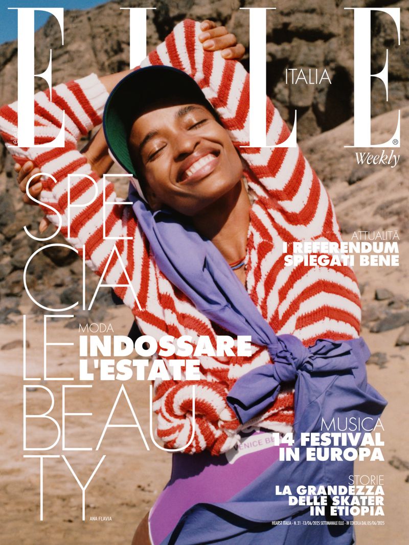 Elle Italia magazine cover featuring a smiling woman with short hair wearing a striped sweater and a lavender wrap with a desert background.