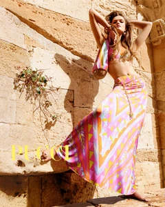 Model Lulu Tenney poses against a sunlit stone wall in an Emilio Pucci colorful printed maxi skirt and matching top.