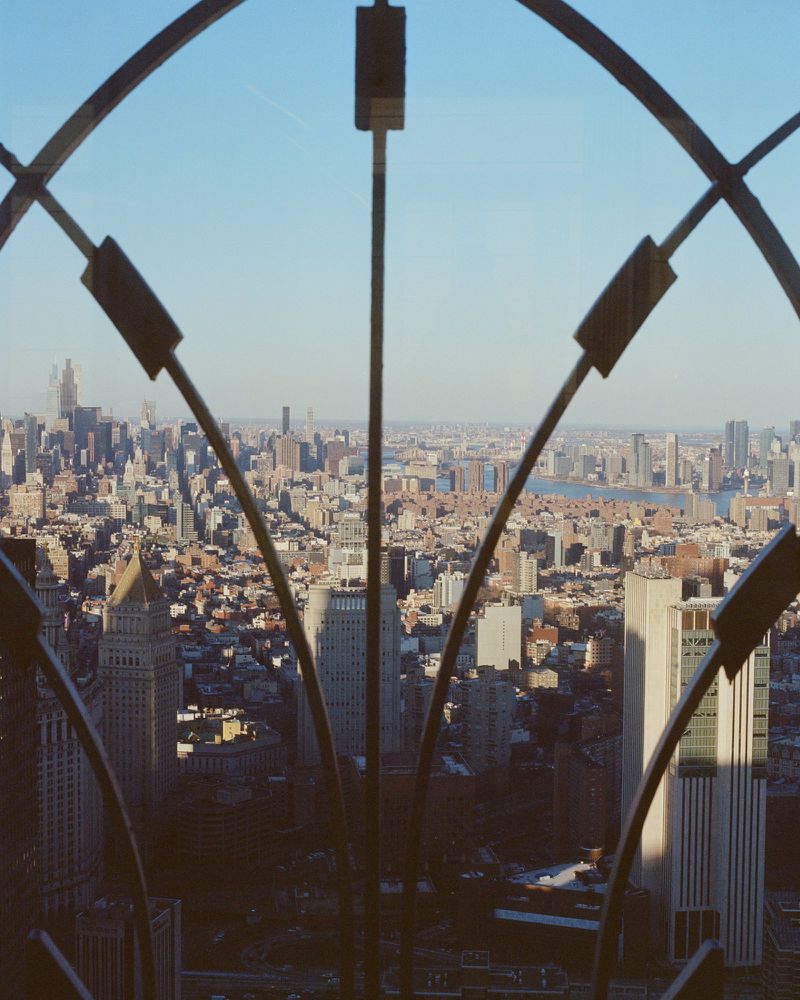 View of an expansive urban cityscape and skyline framed by an arched architectural metal window structure.