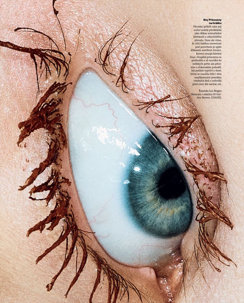 Macro beauty photograph of a blue eye with brown mascara clumped along the upper and lower eyelashes.