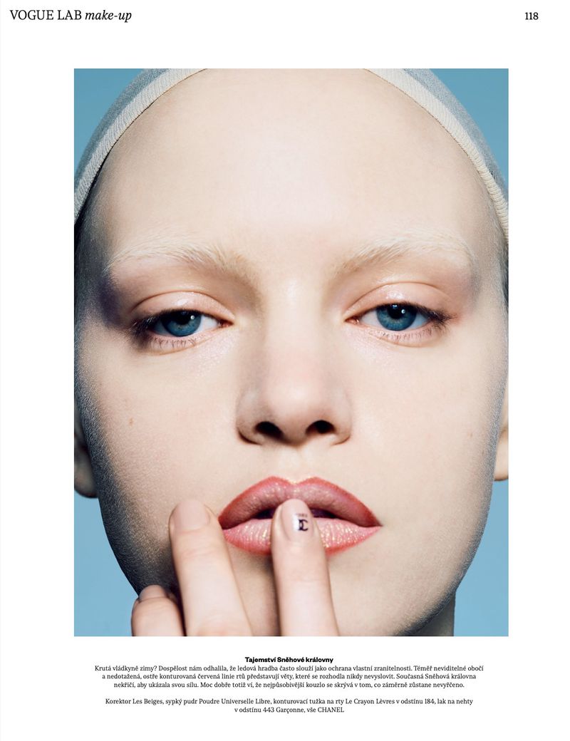 Close-up beauty portrait of model Lise Sauve touching her pink lined lip against a soft blue studio background.