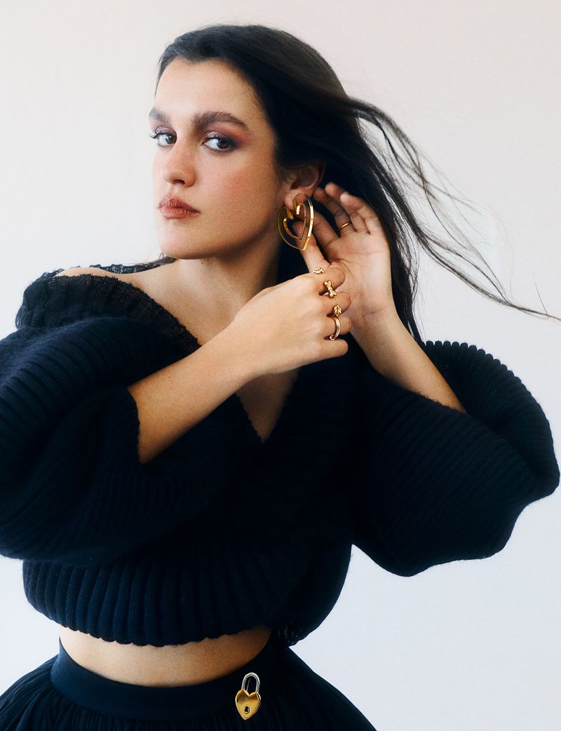 Portrait of Amaia Romero wearing a black knitted top and gold earrings against a light background for Elle Spain