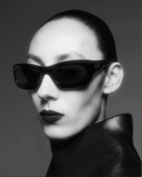Gaia Orgeas wearing bold black Port Tanger sunglasses and a black high-collar leather top in a monochrome studio portrait.
