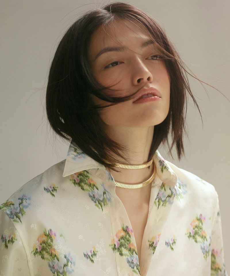 Lisa Han wearing a floral collared shirt and layered gold necklace in a portrait photographed by Alyona Kuzmina.