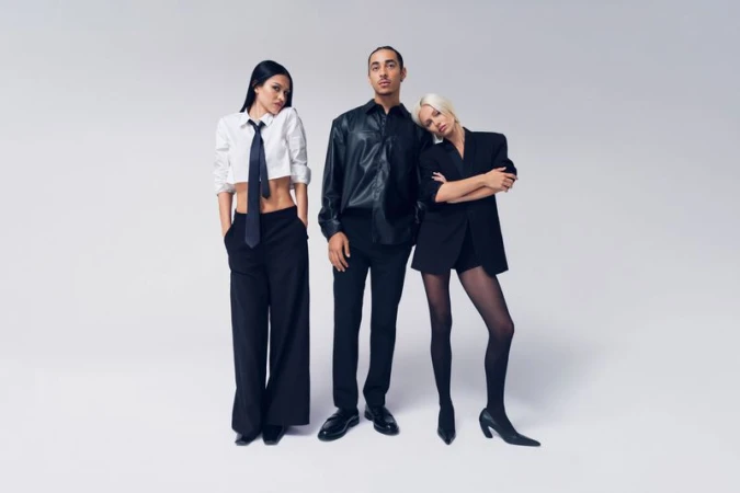 Amelia Gray, Julez Smith, and Delilah Belle pose in tailored black and white outfits against a neutral studio backdrop for H&M.