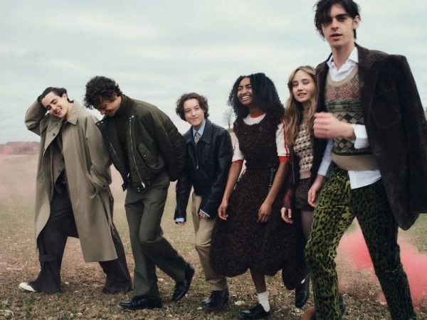 Bella Ramsey and a group of young actors walking outdoors across a rural field wearing eclectic layered fashion for British Vogue.